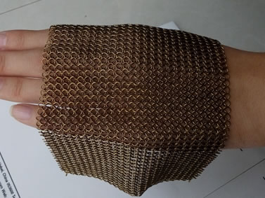 A piece of brass chainmail is on the back of the hand in stretching style.