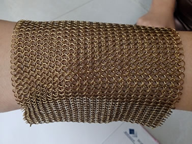A piece of brass chainmail is on the wrist in stretching style.